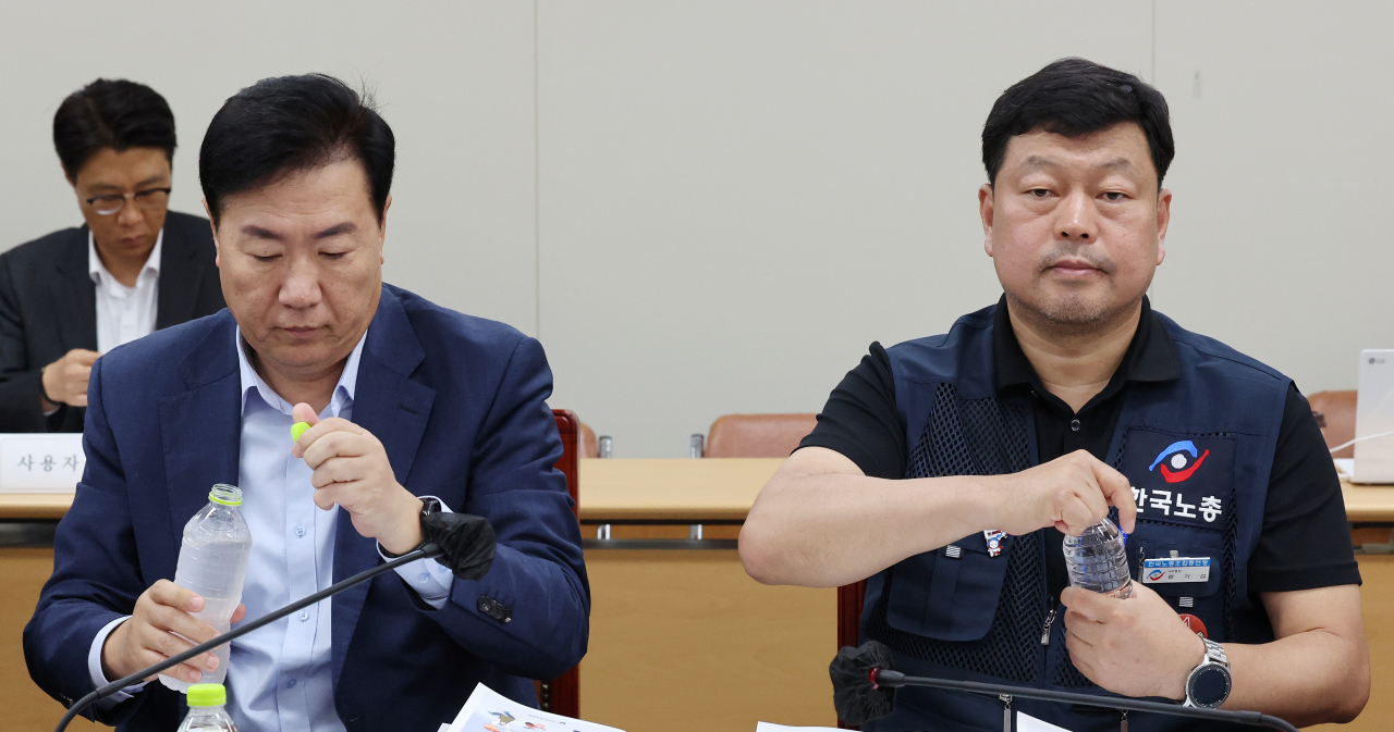 8일 오후 세종시 정부세종청사 최저임금위원회 회의실에서 열린 제3차 전원회의에서 사용자위원인 류기정 한국경영자총협회 전무(왼쪽)와 근로자위원인 류기섭 한국노총 사무총장이 물을 마시기 위해 생수통을 잡고 있다. [연합]