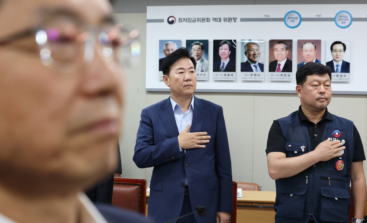박준식 최저임금위원회 위원장을 비롯한 사용자위원, 근로자위원, 공익위원들이 8일 오후 세종시 정부세종청사 최저임금위원회 회의실에서 열린 제3차 전원회의에 참석해 국기에 경례하고 있다. 연합뉴스