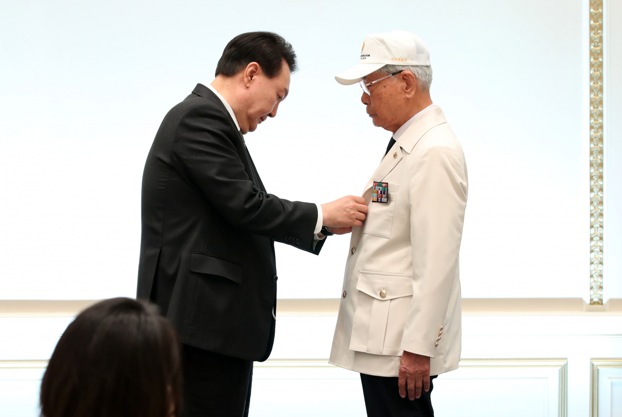 윤석열 대통령이 14일 청와대 영빈관에서 열린 국가유공자 및 보훈가족 초청 오찬에서 대한민국6.25참전유공자회 이하영 이사에게 ‘영웅의 제복’을 직접 입혀주고 있다. [연합]