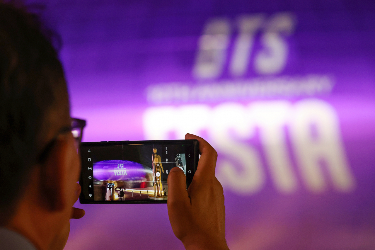 그룹 방탄소년단(BTS) 데뷔 10주년을 하루 앞둔 12일 오후 한 외국인 관광객이 BTS를 상징하는 보랏빛으로 물든 서울 동대문디자인플라자(DDP) 건물을 촬영하고 있다. 이날부터 남산서울타워, 세종문화회관, 세빛섬, 동대문디자인플라자, 롯데월드타워, 서울시청 본관, 반포·월드컵·양화·영동대교 등에서 보랏빛 조명이나 미디어파사드가 펼쳐지는 등 'BTS 10th 애니버서리 페스타' 오프라인 이벤트가 본격적으로 시작된다. [연합]