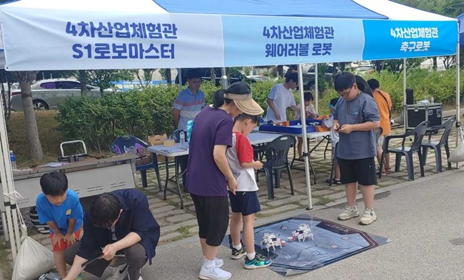 캠핑 페스티벌에 참가한 가족들이 로봇 체험을 하고 있다.