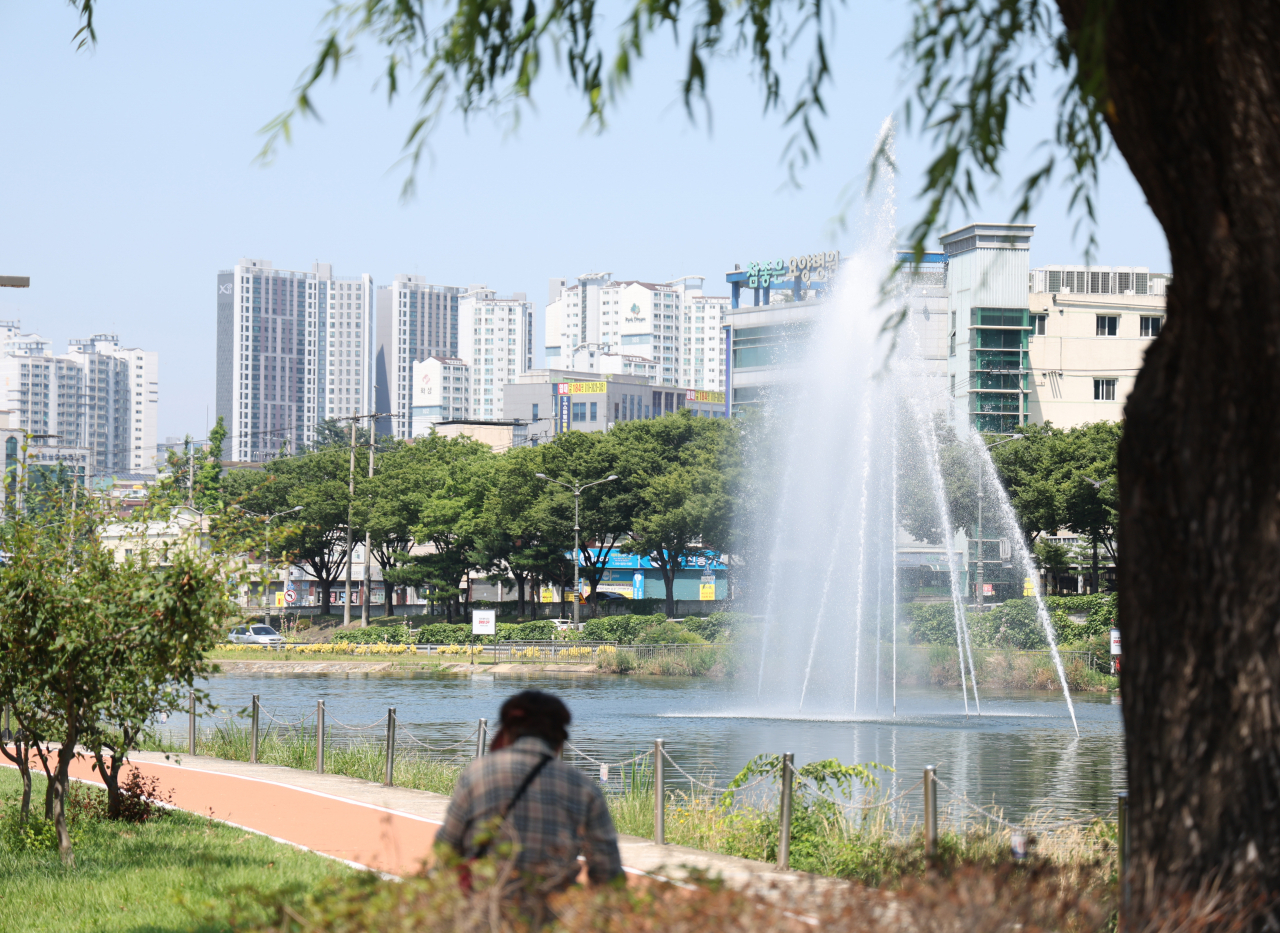 18일 대구 낮 최고기온이 32.8도를 웃돌며 무더위가 기승을 부린 가운데 신천을 찾은 한 시민이 나무 그늘에 앉아 인공 분수를 바라보며 더위를 식히고 있다. [연합]