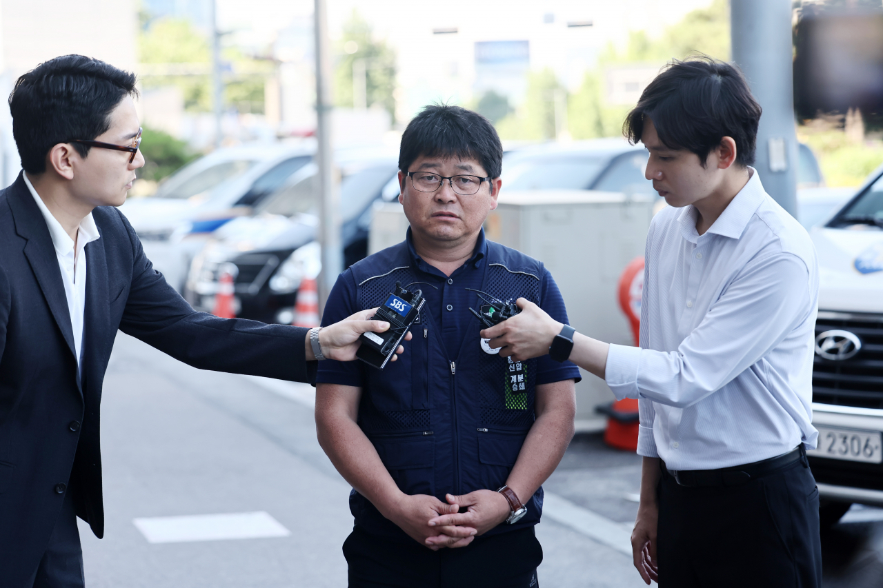 지난달 서울 도심 1박2일 집회와 관련해 경찰 수사를 받는 전병선 민주노총 조직쟁의실장(가운데)이 22일 오전 서울 남대문경찰서로 들어서며 취재진 질문에 답하고 있다. [연합]