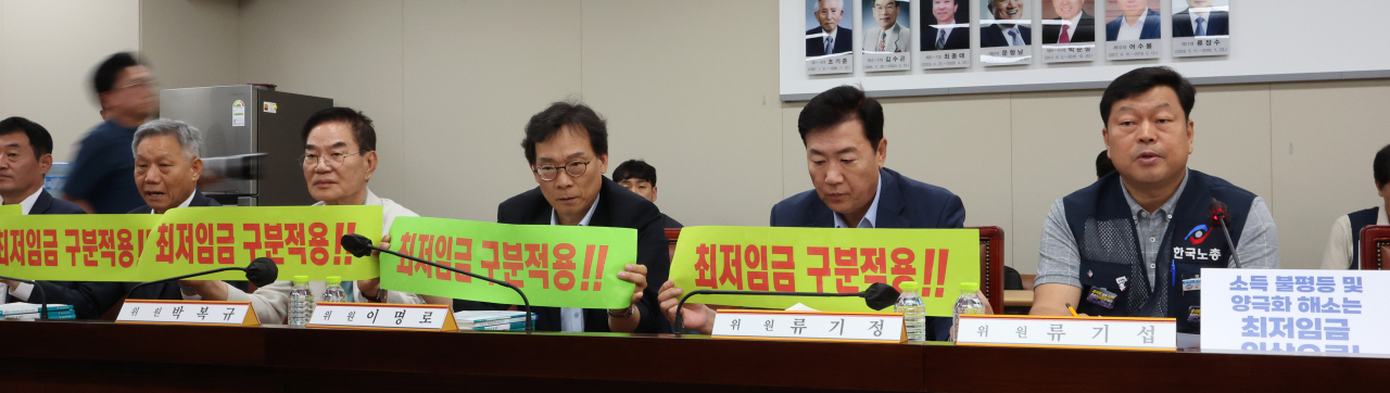 22일 오후 세종시 정부세종청사 최저임금위원회 회의실에서 열린 제7차 전원회의에서 근로자위원인 류기섭 한국노총 사무총장(오른쪽)이 발언을 시작하자 류기정 한국경영자총협회 전무를 비롯한 사용자위원들이 최저임금 구분적용 필요성을 강조하는 손팻말을 들어 보이고 있다. 연합뉴스