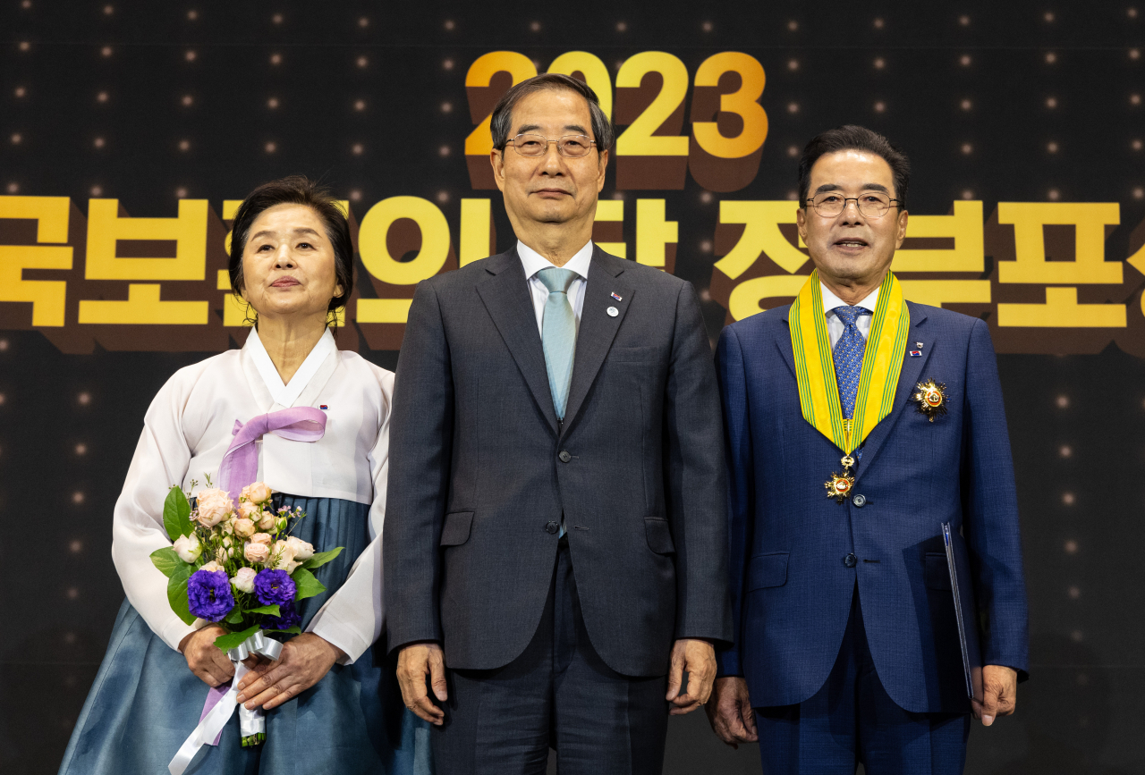 한덕수(가운데) 국무총리가 22일 오전 서울 중구 앰배서더 서울 풀만 호텔에서 열린 호국보훈의 달 정부포상식에 참석해 이성희(오른쪽) 농협중앙회 회장에게 국민훈장 모란장을 전수한 후 기념 촬영하고 있다. [연합]