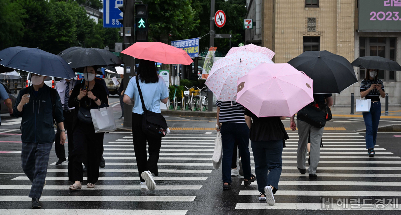 지난 26일 오전 서울 세종대로사거리에서 시민들이 우산을 쓰고 발걸음을 재촉하고 있다. [이상섭 기자]