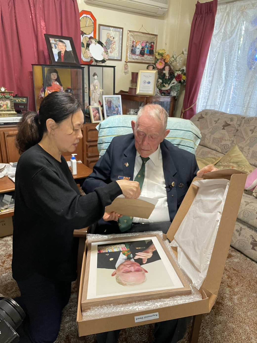 한국전 당시 가평전투에 참전했던 레이먼드 디드씨가 호주 브리즈번의 자택에서 사진을 전달 받고 있다. [한화에어로스페이스 제공]
