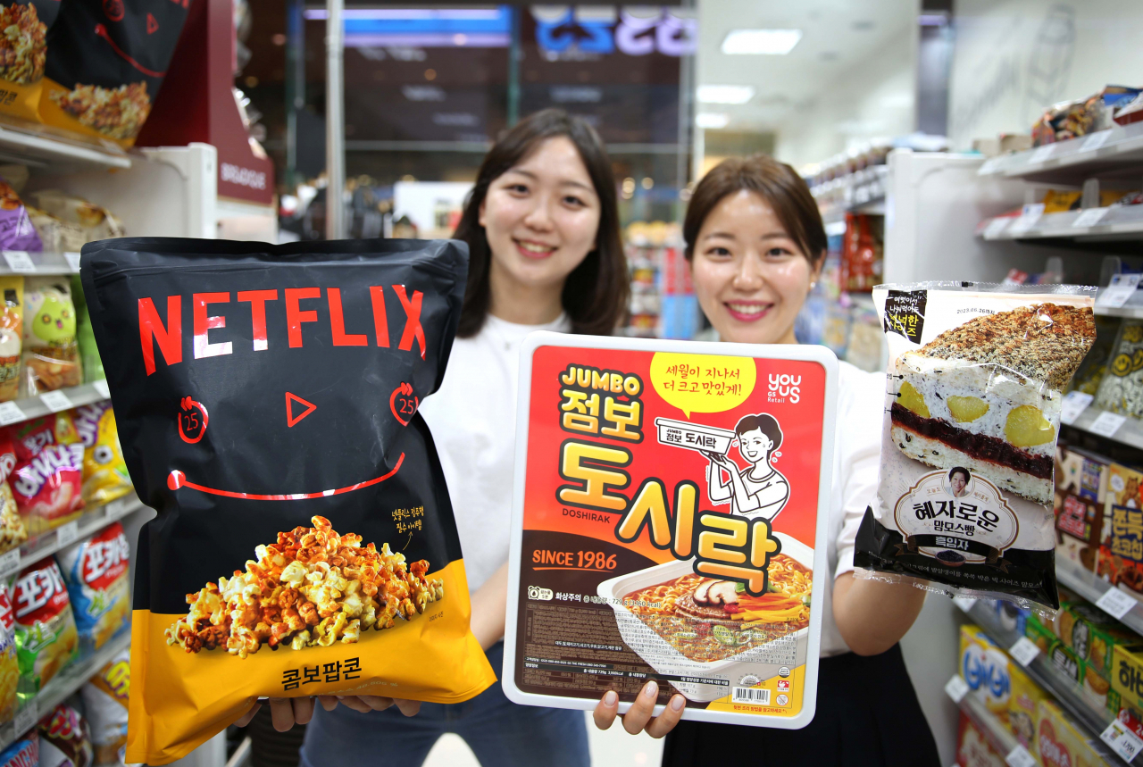모델들이 GS25의 대용량 히트 상품 ‘넷플릭스점보팝콘’, ‘점보 도시락’, ‘혜자로운맘모스빵’을 들고 포즈를 취하고 있다. [GS리테일 제공]