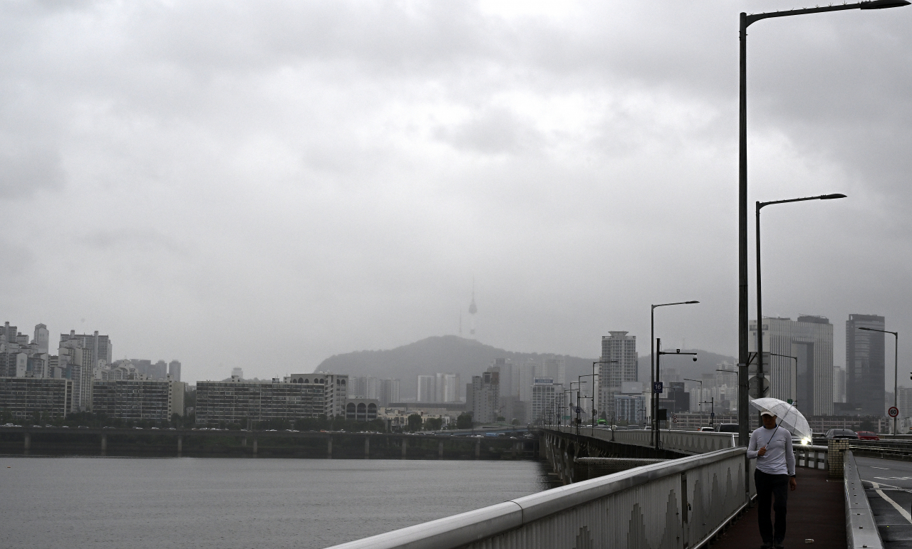 지난 26일 서울 영등포구 여의도 원효대교 남단에서 한 시민이 우산을 쓰고 다리를 건너고 있다. [임세준 기자]
