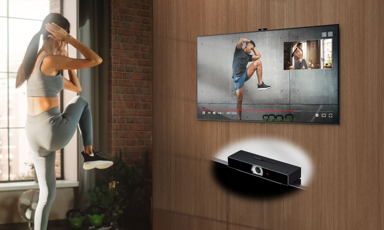 이용자가 LG TV 전용 카메라 LG 스마트 캠을 통해 홈트레이닝 코칭 영상과 본인 동작을 비교하며 운동하고 있다. [LG전자 제공]