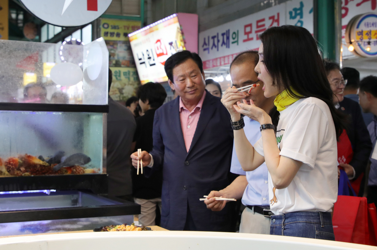 김건희 여사가 3일 오후 강원도 강릉시 중앙·성남시장을 방문해 횟집에서 오징어회를 시식하고 있다. [연합]