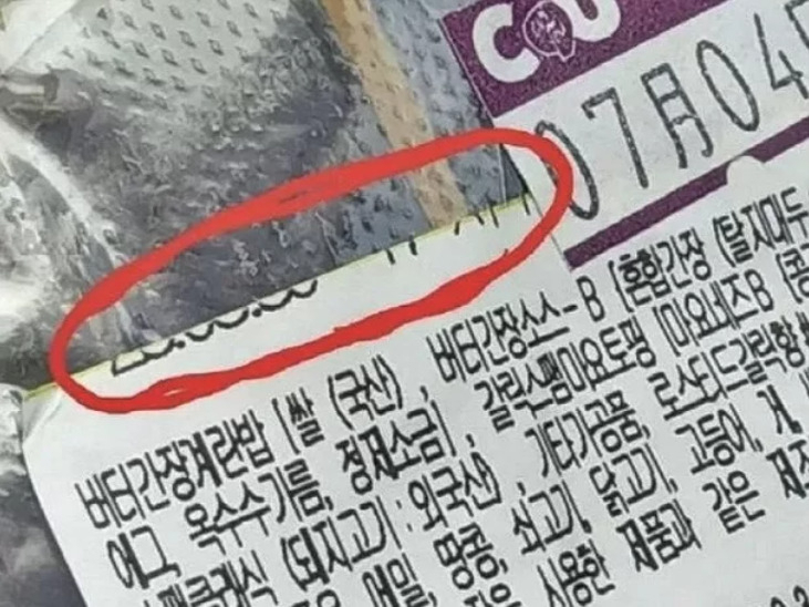 A씨가 올린 편의점 삼각김밥 포장지 사진. 유통기한이 잘린(붉은 색 원) 채 옆에 '7월4일'이라고 적힌 견출지가 붙어있다. 잘리고 남은 원래 날짜 표식 부분이 둥근 것으로 미뤄 유통기한은 최소 6월 30일까지라고 A씨는 주장했다. [온라인 커뮤니티 갈무리]