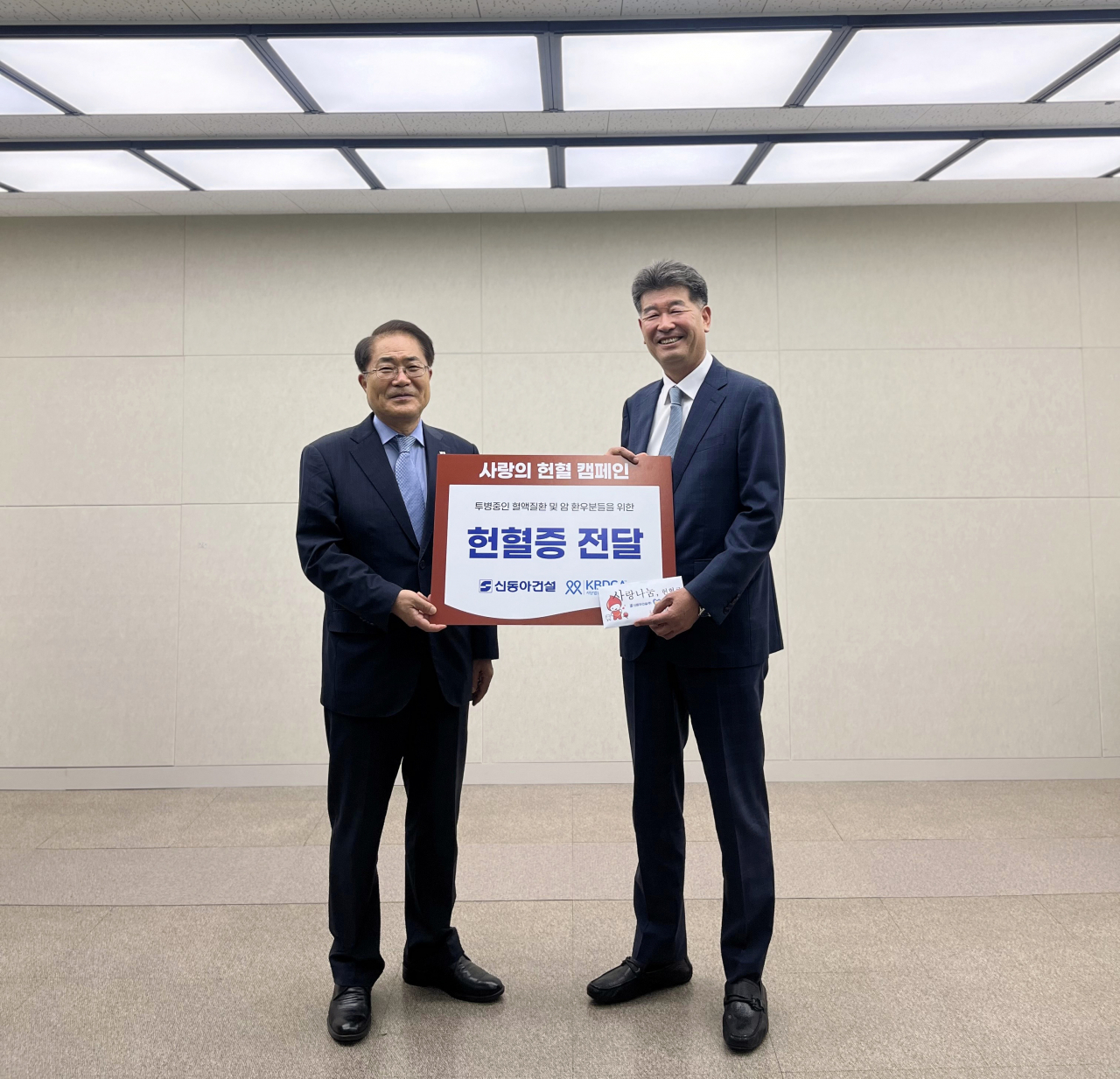 진현기 신동아건설 대표이사(사진 오른쪽)가 장태평 한국혈액암협회장(사진 왼쪽)에게 헌혈증을 전달하며 기념촬영을 하고 있다. [신동아건설 제공]