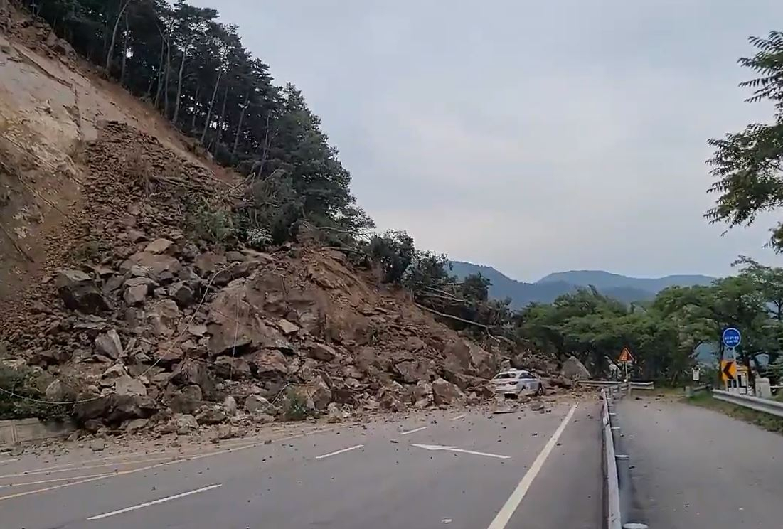 A landslide hits a passing taxi on Thursday in the southwestern city of Jeongeup, 180 kilometers of Seoul, with police controlling the area on Friday. (Yonhap)