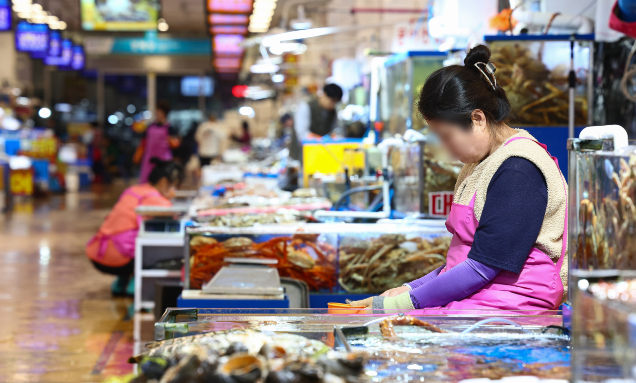 Fishmonger at Seoul’s Noryangjin seafood market, fells sleep while she waits for customers, Friday. (Yonhap)