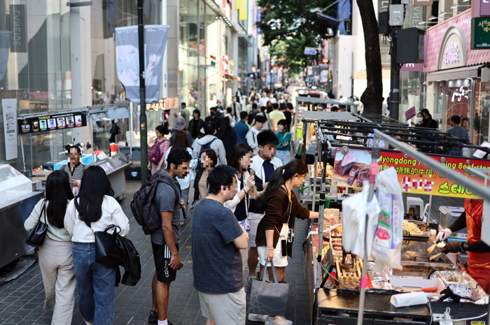 Tourists visit food stalls in Myeong-dong in May. (Yonhap)