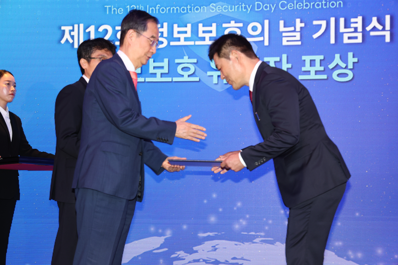 한덕수 국무총리가 12일 오전 서울 중구 롯데호텔에서 열린 정보보호의 날 기념식에 참석해 이만수 (주)한국통신인터넷기술 대표이사에게 철탑산업훈장을 전달하고 있다. [연합]