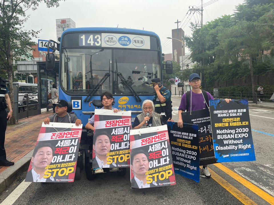 전국장애인차별철폐연대(전장연) 활동가들이 13일 오전 서울 종로구 혜화동로터리 중앙버스전용차로에서 오세훈 시장을 규탄하며 시내버스를 막아서고 있다. [연합]