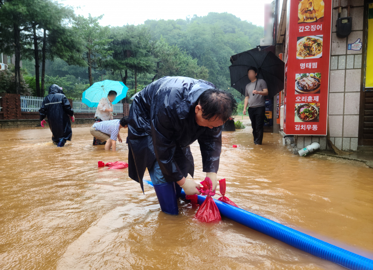 14일 전북 군산시 구암동 한 상가 건물 인근 도로가 이틀째 내린 집중호우로 침수돼 공무원과 주민들이 배수 작업을 하고 있다. [연합]