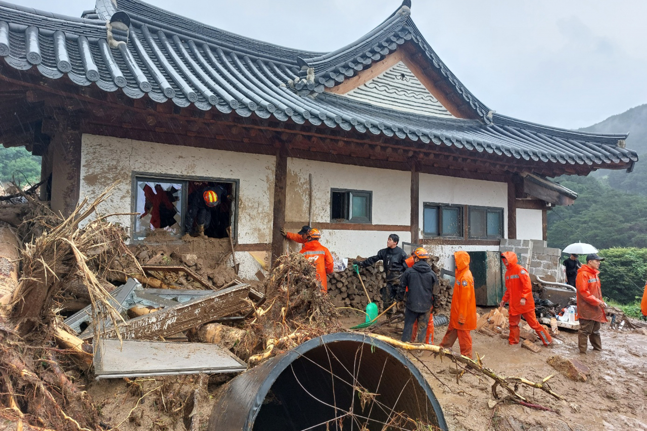 15일 경북 봉화군 춘양면 학산리에서 많은 비로 토사가 주택을 덮쳐 소방관들이 현장 수습에 나서고 있다. [연합]