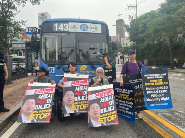 전국장애인차별철폐연대(전장연) 활동가들이 13일 오전 서울 종로구 혜화동로터리 중앙버스전용차로에서 오세훈 시장을 규탄하며 시내버스를 막아서고 있다. [연합]