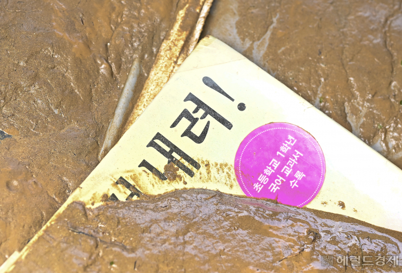 17일 충청북도 청주시 궁평2지하차도 입구에 한 침수차량이 견인되어 놓여진 가운데 뒷자리 책자에 '내려' 라는 글귀가 적힌 교재가 보이고 있다. 해당 차량의 탑승자가 초등학생이 있었을 것으로 추정되는 가운데 당사자와 가족은 무사히 차량에서 빠져 나왔을지 취재를 하며 걱정이 되었다. 청주=임세준 기자