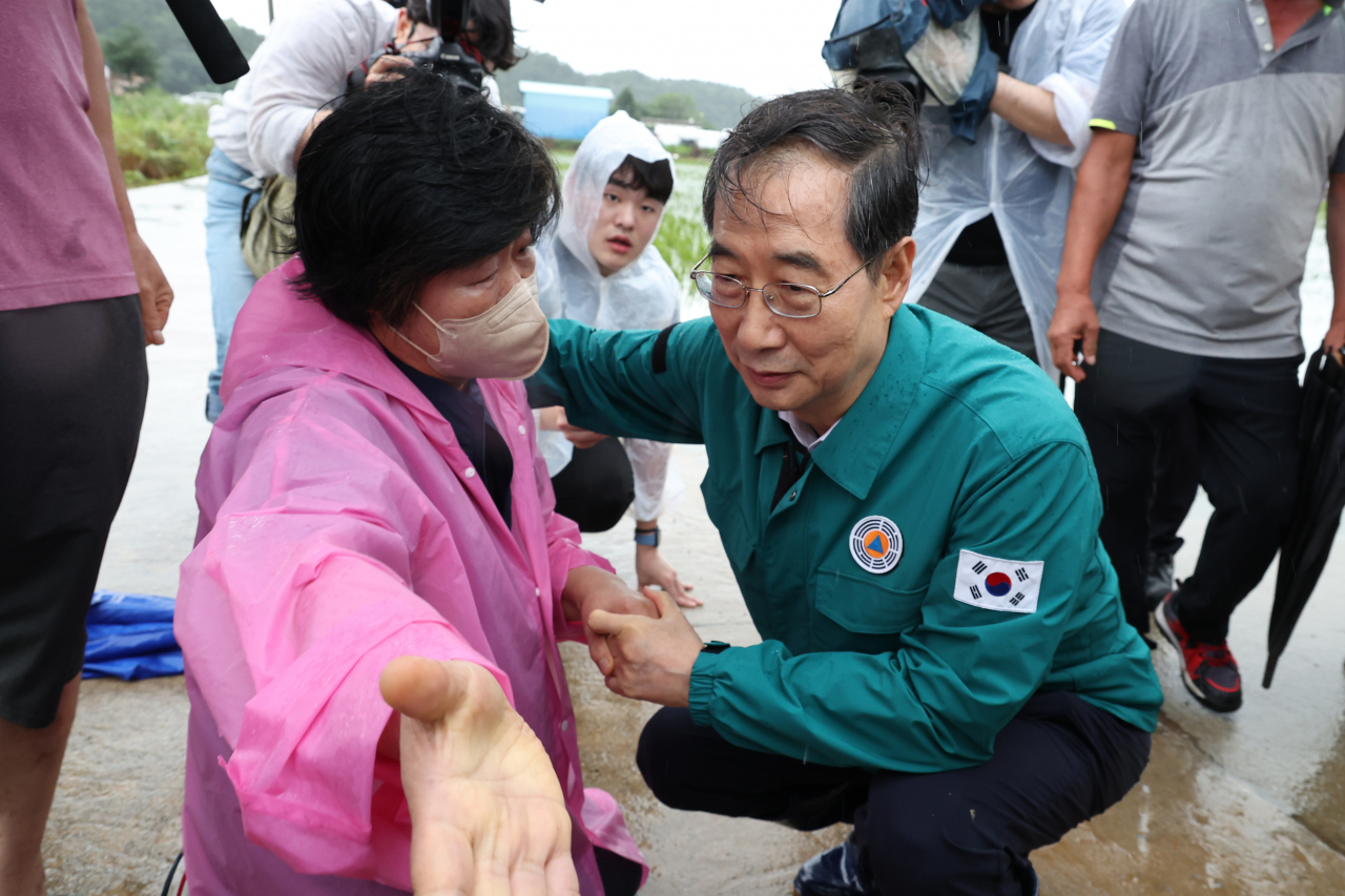 한덕수 국무총리가 18일 오후 집중호우로 침수됐던 전북 익산시 용안면을 방문, 피해 상황을 이야기하기 위해 무릎을 꿇은 주민을 위로하고 있다. 연합뉴스