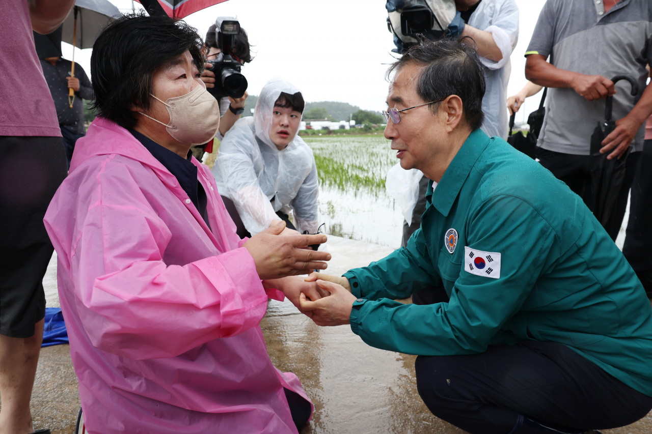 한덕수 국무총리가 18일 오후 집중호우로 침수됐던 전북 익산시 용안면을 방문, 피해 상황을 이야기하기 위해 무릎을 꿇은 주민을 위로하고 있다. [연합]