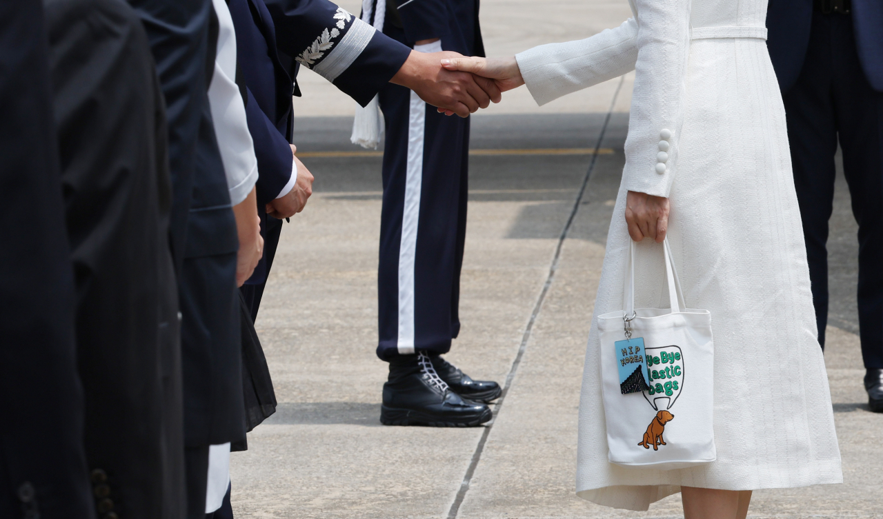 윤석열 대통령과 함께 리투아니아에서 열리는 북대서양조약기구(NATO.나토) 정상회의 참석과 폴란드 방문에 나서는 김건희 여사가 10일 성남 서울공항에 도착, 환송객들과 인사하고 있다. 김 여사는 이날 바이바이 플라스틱 백이라는 문구가 적힌 에코백에 힙 코리아(HIP KOREA)라고 적힌 키링(열쇠고리)을 매달았다. [연합]