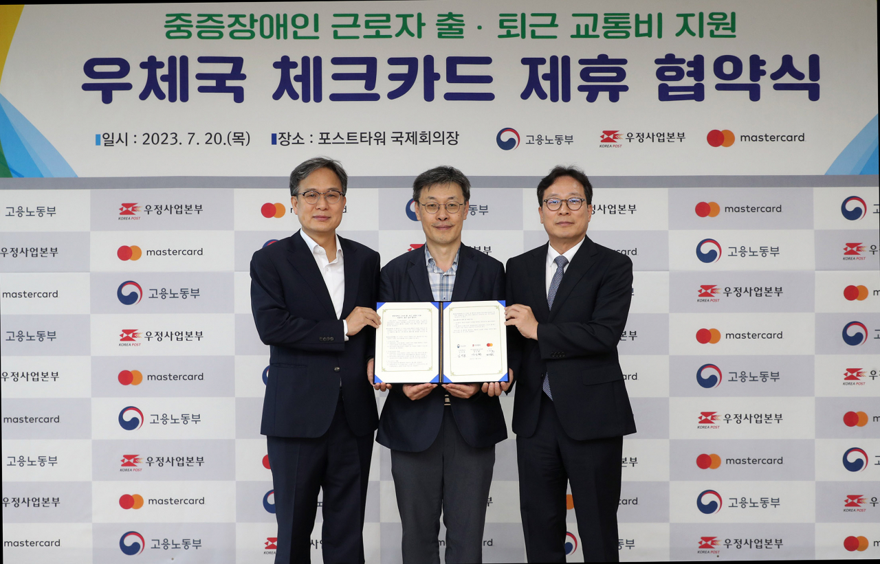 고용노동부와 우정사업본부, 마스터카드 코리아는 20일 중증장애인 근로자 출퇴근 교통비 지원사업을 활성화하기 위해 전용 카드 신규 출시 업무협약(MOU)을 체결했다. MOU 이후 기념촬영을 하고 있는 김성호 고용부 고용정책실장(가운데)이 미소 짓고 있다. [고용노동부 제공]