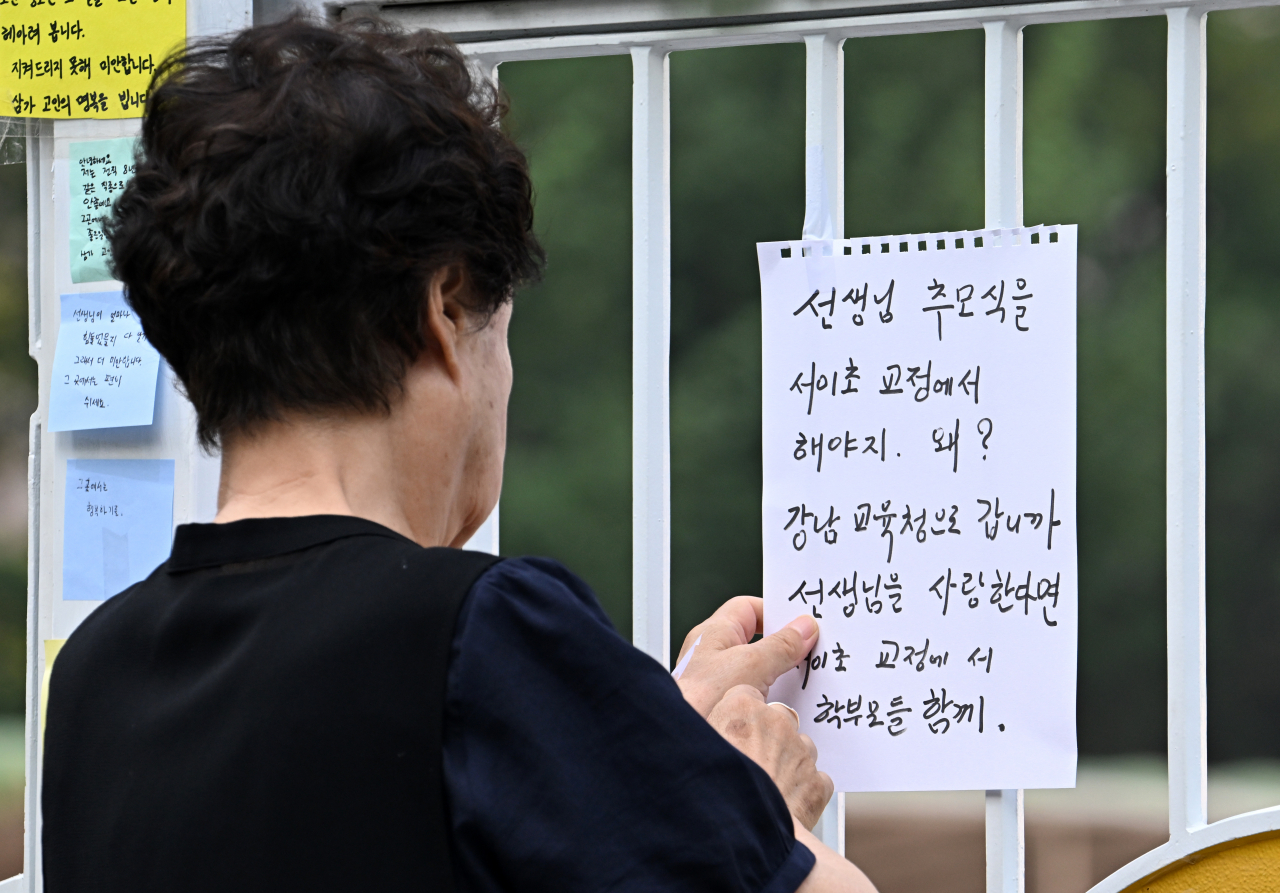 21일 서울 서초구 서이초등학교 정문을 찾은 한 시민이 애도하며 비판하는 메모지를 부착하고 있다. 지난 18일 서이초초등학교 담임교사 A씨가 교실 안에서 숨진 채 발견됐다. A씨는 극단적 선택을 한 것으로 알려졌다. 임세준 기자