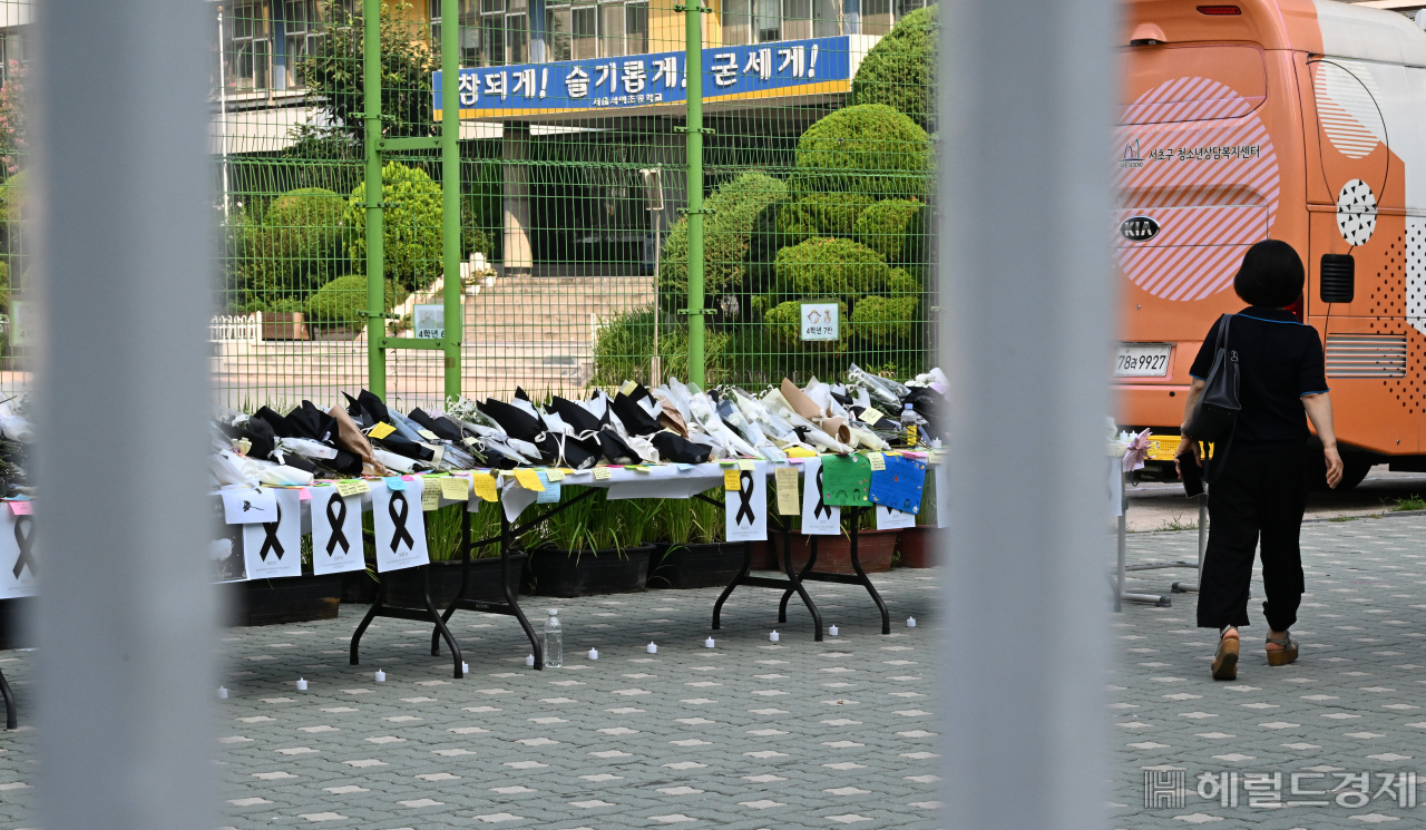 서이초등학교에서 학교 관계자가 교내로 들어서고 있다. 옆으로 추모식에 놓여진 꽃다발들이 보이고 있다. 임세준 기자