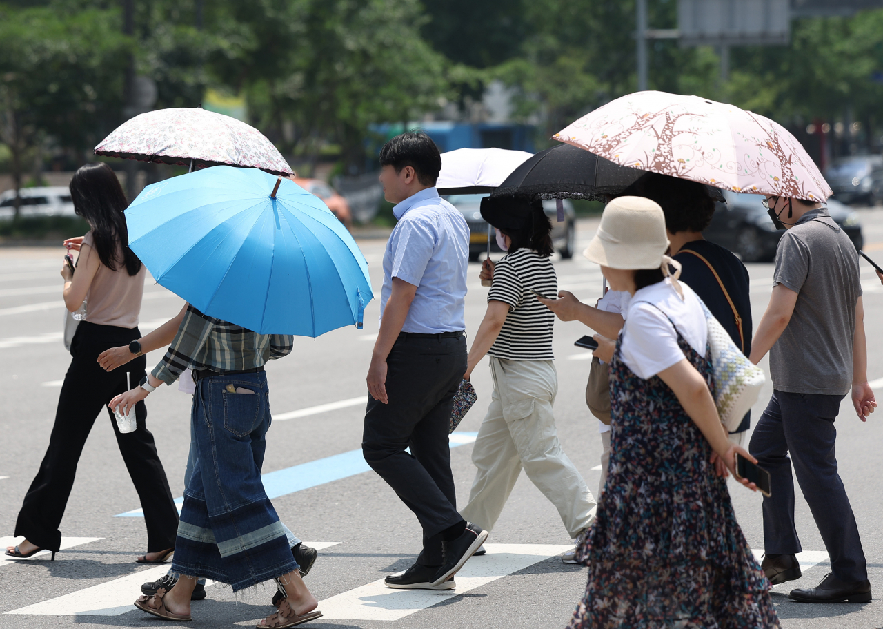 중복을 맞은 21일 전국적으로 무더운 날씨가 이어진 가운데 시민들이 서울 광화문에서 우산과 양산을 쓴 채 횡단보도를 건너고 있다. [연합]