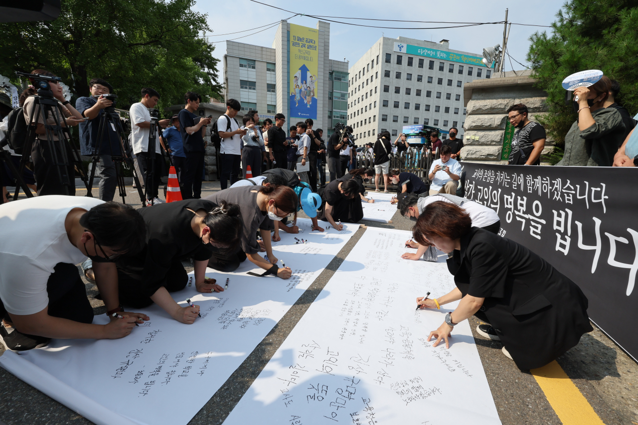 서이초등학교에서 신규교사가 극단적 선택을 한 것과 관련해 전국교직원노동조합 조합원들이 20일 오후 서울시교육청 앞에서 열린 추모 행사에서 추모글을 적고 있다. [연합]