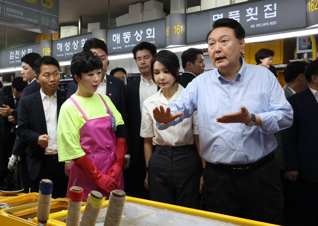 윤석열 대통령이 27일 부산 중구 자갈치시장에서 직접 뜰채로 건져 올린 장어를 상인에게 건네며 요리방법을 설명하고 있다. [연합]