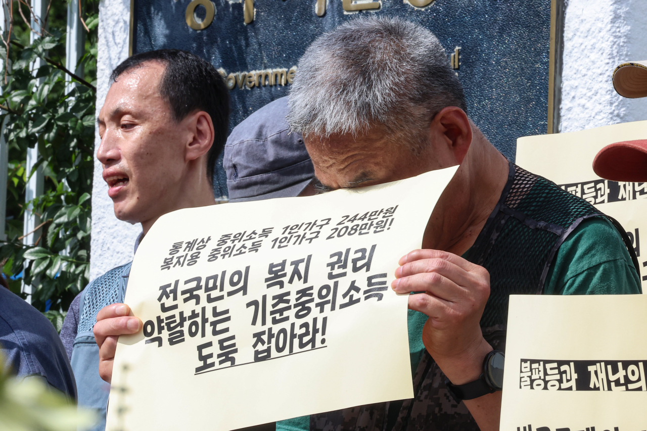 아침부터 일부 지역에 폭염경보가 발효된 28일 오전 서울 종로구 정부서울청사 앞에서 열린 기준중위소득 현실화 기자회견에서 한 참가자가 팻말로 흐르는 땀을 닦고 있다. [연합]