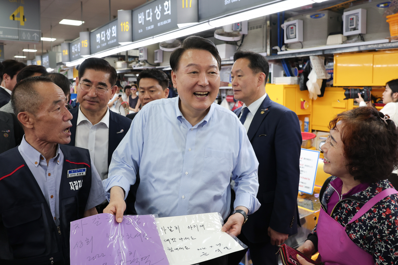 윤석열 대통령이 27일 부산 중구 자갈치시장에서 윤 대통령 본인의 사인을 모아온 한 상인과 인사하고 있다. [연합]