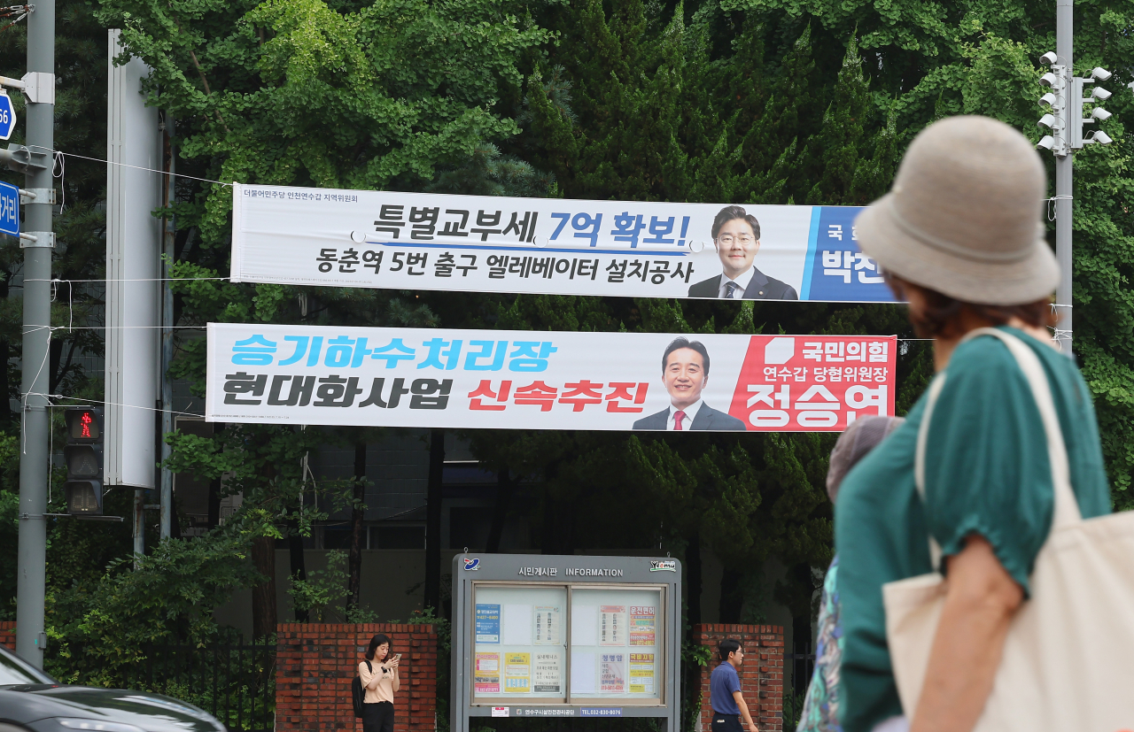 인천시 연수구 소금밭사거리에서 연수구청 관계자들이 시 조례위반 정당현수막을 강제 철거에 앞서 한 시민이 정당현수막을 바라보고 있다. [연합]