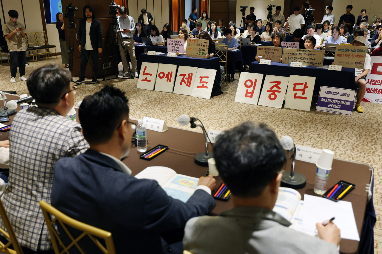 Civic groups protest a pilot project to introduce 100 foreign domestic workers in the middle of a public hearing, holding signs that read "Stop the introduction of slavery." (Yonhap)