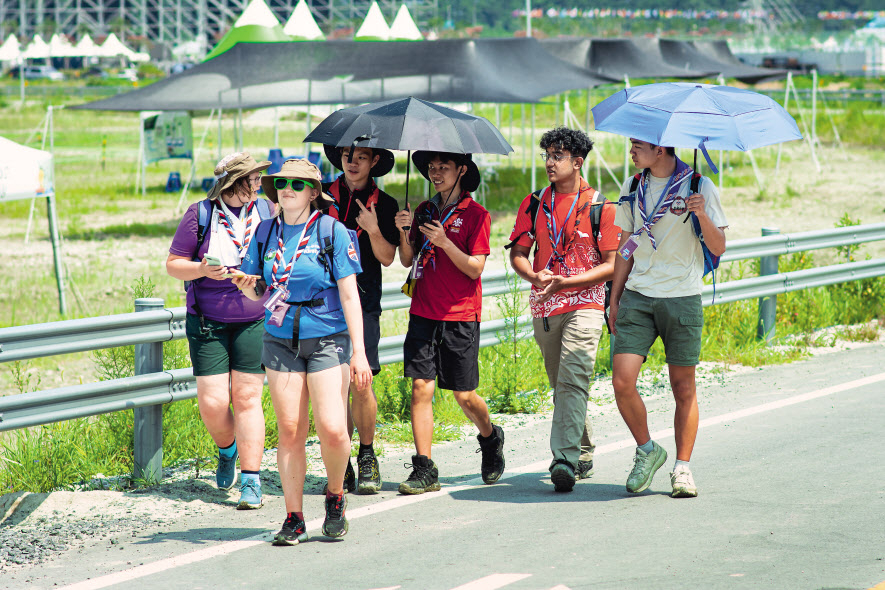 제25회 세계스카우트 잼버리가 개막한 1일 전북 부안군 새만금 부지에서 스카우트 대원들이 양산으로 더위를 피하며 걸어가고 있다. 새만금 야영지에서는 첫날부터 21명의 온열질환자가 발생하는 등 폭염이 기승을 부리고 있다. [연합]