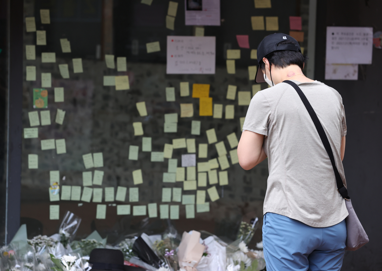 지난 25일 오후 서울 관악구 신림역 인근 상가 골목에 마련된 흉기난동 사건으로 숨진 20대 남성 피해자 A씨를 위한 추모 공간에서 한 시민이 기도를 하고 있다. [연합]