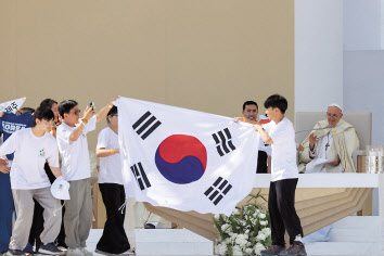 6일(현지시간) 포르투갈 리스본의 테주 공원에서 열린 올해 세계청년대회 폐막 미사에서 프란치스코 교황(오른쪽)이 2027년 차기 대회 개최지를 서울로 발표하자 한국의 청년들이 무대 위에서 태극기를 펼쳐 들며 환호하고 있다. [AP]