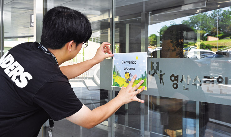8일 경기도 파주시 영산수련원에서 한 관계자가 스페인어로 적힌 환영 인사 ‘Bienvenido a Corea’(한국에 오신 걸 환영합니다) 문구를 출입문에 붙이고 있다. 영산수련원에는 스페인 참가자 200여 명이 입소할 예정이다. 파주=임세준 기자
