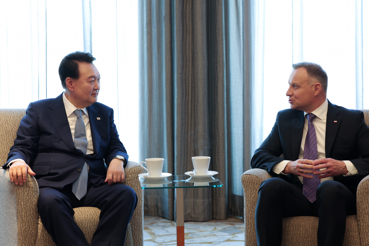 South Korean President Yoon Suk Yeol (left) and Polish President Andrzej Duda share a conversation before the Korea-Poland business forum in Warsaw, Poland, July 14. (Yonhap)