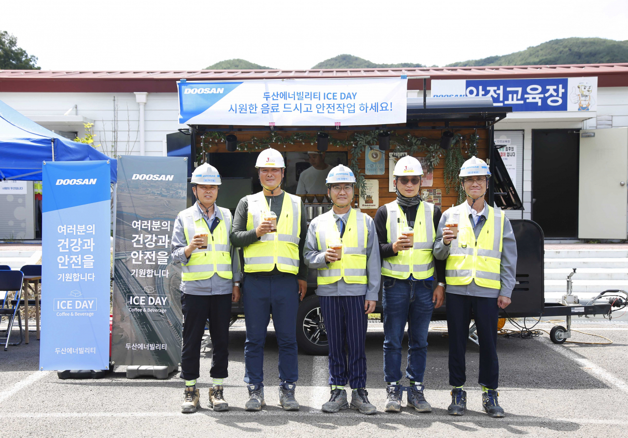 경남 합천군에 위치한 함양-창녕간 고속도로 건설현장에서 두산에너빌리티와 협력사 직원들이 커피차 앞에서 기념촬영을 하고 있다. [두산에너빌리티 제공]