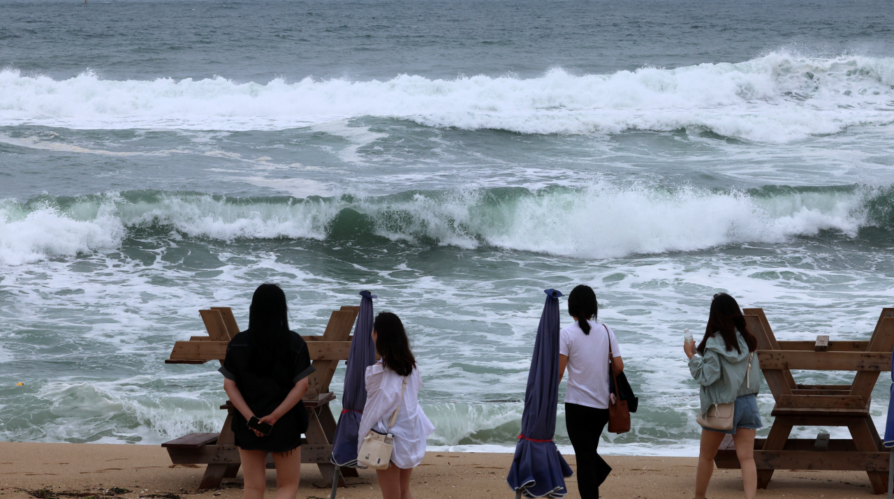 Tourists walk along Gangmun beach, Gangneung, Gangwon Province, as swimming has been banned due to high waves caused by Typhoon Khanun as it approaches, Tuesday. (Yonhap)