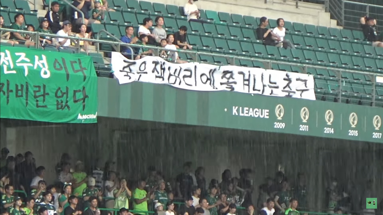 A screenshot image shows Jeonbuk Hyundai Motors FC fans hold a banner that reads "Soccer kicked out by failed Jamboree," at Jeonju World Cup Stadium in Jeonju, North Jeolla Province, Sunday. (YouTube channel Jeonbuk Hyundai Sangyounggwan)