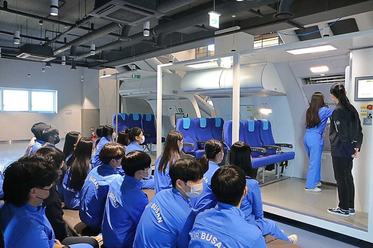 에어부산 ‘꿈담기 드림 교실’에 참여한 학생들이 비상문 작동법 교육을 받고 있다. [사진=에어부산]