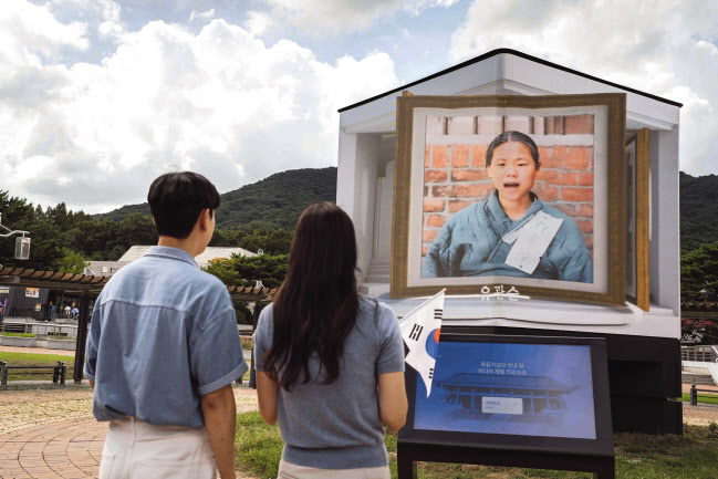 독립기념관에 설치된 미디어 아트 조형물. 관람객이 인공지능(AI) 이미지 복원기술로 재현된 유관순 열사의 동영상을 보고 있다. [SK텔레콤 제공]