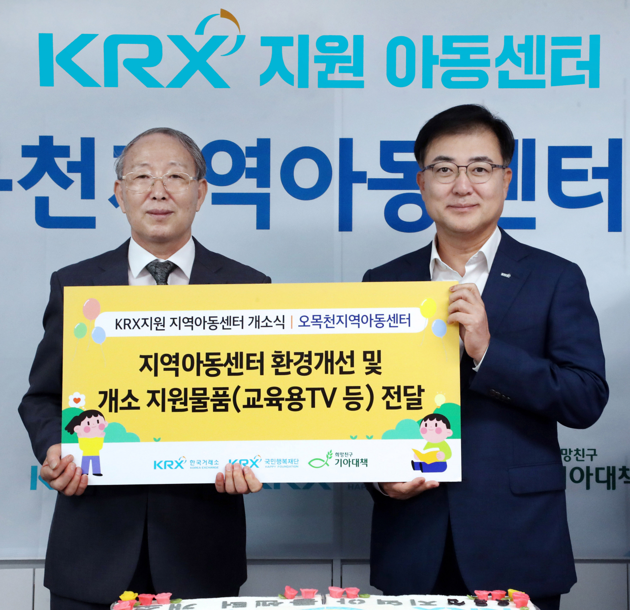 손병두(오른쪽) 한국거래소 이사장과 오경식 오목천지역아동센터 대표가 경기도 수원특례시 오목천지역아동센터의 리모델링 공사 완공을 기념하는 ‘KRX지역아동센터’ 개소식에서 기념품을 전달한 후 기념 촬영을 하고 있다. [한국거래소]